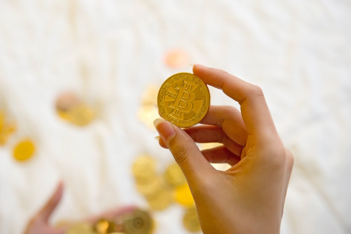 person holding gold round coin